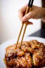 Preparato saporito pollo piccante su piatto bianco su tavolo di legno in ristorante asiatico — Foto stock
