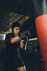 Молодий азіатський майстер тренує бокс, виконуючи удари під час фізичних вправ з важким балончиком у сучасному спортзалі — стокове фото