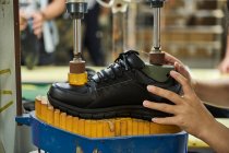 Detalle de las manos de la mujer mientras revisa los zapatos en la línea de producción de control de calidad en la fábrica de zapatos chinos - foto de stock