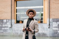 Портрет элегантного черного мужчины в сером пальто на улице, смотрящего в сторону — стоковое фото