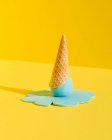 Mockup blue melting ice in waffle cone platziert auf gelbem Hintergrund repräsentiert Sommer-Konzept — Stockfoto