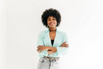 Feliz joven afroamericana femenina con hermoso pelo afro en traje de moda que tiene sobre fondo blanco - foto de stock