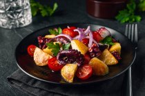 Salada saborosa com polvo e legumes variados e ervas na placa na mesa — Fotografia de Stock