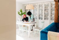 Junge multiethnische Modedesignerinnen diskutieren Skizzen für neue Kollektion, während sie gemeinsam an einem Tisch im hellen Raum arbeiten — Stockfoto