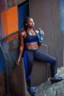 Sportliche ethnische Frau trinkt Wasser — Stockfoto