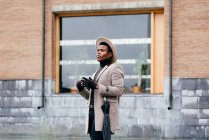 Retrato de hombre negro elegante con abrigo gris en la calle mirando hacia otro lado - foto de stock