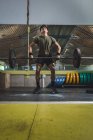 Focalisé asiatique athlète masculin faisant haltérophilie avec haltère lourd pendant l'entraînement dans la salle de gym avec les yeux fermés — Photo de stock