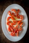 Draufsicht auf appetitliche Tomatenstücke mit grünen Kräutern, serviert auf Teller auf Holztisch — Stockfoto