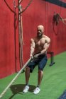 Strong sportsman pulling rope with heavy weights during intense workout in contemporary gym — Stock Photo