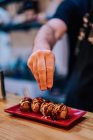 Gesichtsloser Koch gießt mit Gewürzen runde Fleischgerichte mit Soße auf stilvollem Teller in Ramen-Bar — Stockfoto