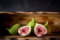 Ripe halved and whole figs placed on wooden rustic table — Stock Photo