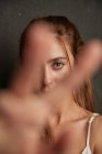 Jovem mulher concurso estendendo a mão para a câmera no fundo cinza no estúdio — Fotografia de Stock