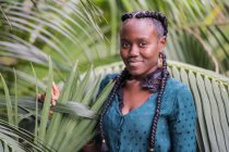 Elegante affascinante bella signora afroamericana con trecce africane guardando la fotocamera nel parco verde — Foto stock