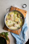 From above top view of metal saucepan with delicious seafood soup with clams and hake placed on wooden board in kitchen — Stock Photo