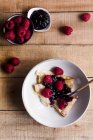 Верхний вид на вкусные блины со сладким клубничным вареньем на тарелке рядом с ложкой на деревянном столе — стоковое фото