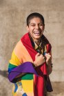 Вміст молодої бісексуальної етнічної жінки з закритими очима та різнокольоровим прапором, що представляє символи ЛГБТК у сонячний день — стокове фото