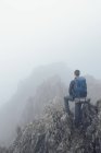 Visão traseira do caminhante masculino anônimo em pé em terras altas rochosas no dia nebuloso durante o trekking no País de Gales — Fotografia de Stock