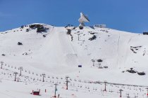 D'en bas de l'antenne satellite sur la montagne enneigée contre la façade du bâtiment sous un ciel nuageux en Espagne — Photo de stock