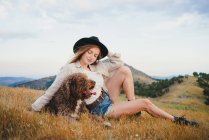 Proprietaria donna con cane Labradoodle obbediente seduto in montagna distogliendo lo sguardo — Foto stock
