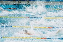 De cima vista lateral de pessoas mergulhando na água com salpicos na piscina com pistas de natação — Fotografia de Stock