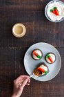 Top view of cropped unrecognizable person hand eating delicious vegetable cupcakes with small carrot sweet decoration on top placed on plate on wooden table — Stock Photo