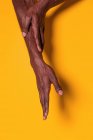 Crop view of anonymous muscular black man touching his forearm with hand on yellow background — Stock Photo