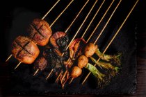 De dessus composition de brochettes grillées savoureuses avec viande, poisson, calmar et brocoli dans le café — Photo de stock