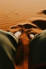 De acima de turista irreconhecível sentado na duna de areia e admirando majestoso cenário do pôr do sol no deserto em Marrocos — Fotografia de Stock