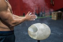 Seitenansicht eines nicht wiederzuerkennenden muskulösen Athleten, der beim Gewichtheben-Training im Fitnessstudio Kreide auf den Händen verteilt — Stockfoto