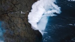 Drone vista di scenario mozzafiato di onde marine schiumose schiantarsi sulla ruvida costa rocciosa — Foto stock