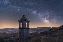 Paesaggio incredibile con cappella in pietra invecchiata nella valle montuosa sotto il cielo serale con Via Lattea e luce del tramonto — Foto stock