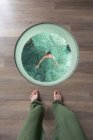 Kopf einer Asiatin mit offenen Armen und geschlossenen Augen im Badeanzug entspannt sich im Schwimmbad auf den Malediven, während eine zierliche Person zu Fuß von oben zusieht — Stockfoto