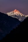 Montañas rocosas del Himalaya cubiertas de nieve iluminadas por la brillante luz del sol naranja en Nepal - foto de stock