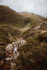 Vue pittoresque de l'eau bouillonnante avec des roches et des fougères dans la vallée montagneuse de Glencoe au Royaume-Uni en été — Photo de stock