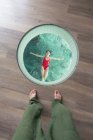 Au-dessus de la femelle asiatique avec les bras ouverts et les yeux fermés en maillot de bain relaxant dans la piscine aux Maldives tandis qu'une personne cultivée pied debout regardant d'en haut — Photo de stock