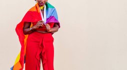 Stilvolle Afroamerikanerin in trendiger Kleidung mit bunter Flagge blickt während der Feier in die Kamera — Stockfoto