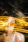 Autosicuro giovane donna afroamericana con i capelli ricci in occhiali da sole alla moda e top rilassante in strada in serata vicino a congelare le luci — Foto stock