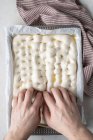 Top view of faceless person preparing raw dough for bread placed on baking paper on table — Stock Photo