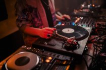 Vista laterale del DJ maschile che mescola musica sul controller durante il concerto nel dark nightclub — Foto stock