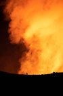 Silhouette of anonymous traveler standing against orange fume of active volcano in Iceland — Stock Photo