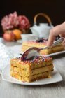 Crop anonymous person with spoon eating tasty traditional Turron de Dona Pepa cake with colorful dragee and nougat served on plate on table — Stock Photo