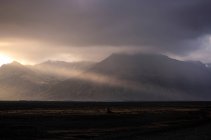 Гірський хребет, розташований на тлі хмарного сходу сонця в туманному ранкові в сільській місцевості Ісландії. — стокове фото