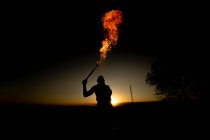 Mujer devoradora de fuego realizando fuego de saliva al atardecer - foto de stock