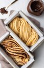 Ungekochter Babka-Kuchen mit Schokoladenpaste auf Backpapier in Metallschale in der Küche gelegt — Stockfoto