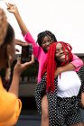 Африканка - американка, яка фотографує смішну дівчину і віддає голубку найкращому другові з піднятою рукою. — стокове фото