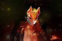 Анонимная женщина в маске креативной лисы с неоновыми орнаментами, работающая во время вечеринки в ночном клубе — стоковое фото