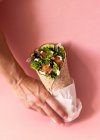 Cortado mãos pessoa irreconhecível segurando envoltório falafel vegan no fundo rosa colorido — Fotografia de Stock