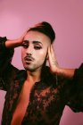 Porträt einer glamourösen Transgender-bärtigen Frau in raffiniertem Make-up, die vor rosa Hintergrund im Studio vor der Kamera posiert — Stockfoto