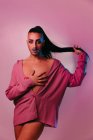 Portrait of glamorous transgender bearded woman in sophisticated make up posing against pink background at studio looking at camera — Stock Photo