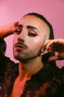 Ritratto di donna barbuta transgender glamour in sofisticato make up posa guardando la fotocamera contro sfondo rosa in studio — Foto stock
